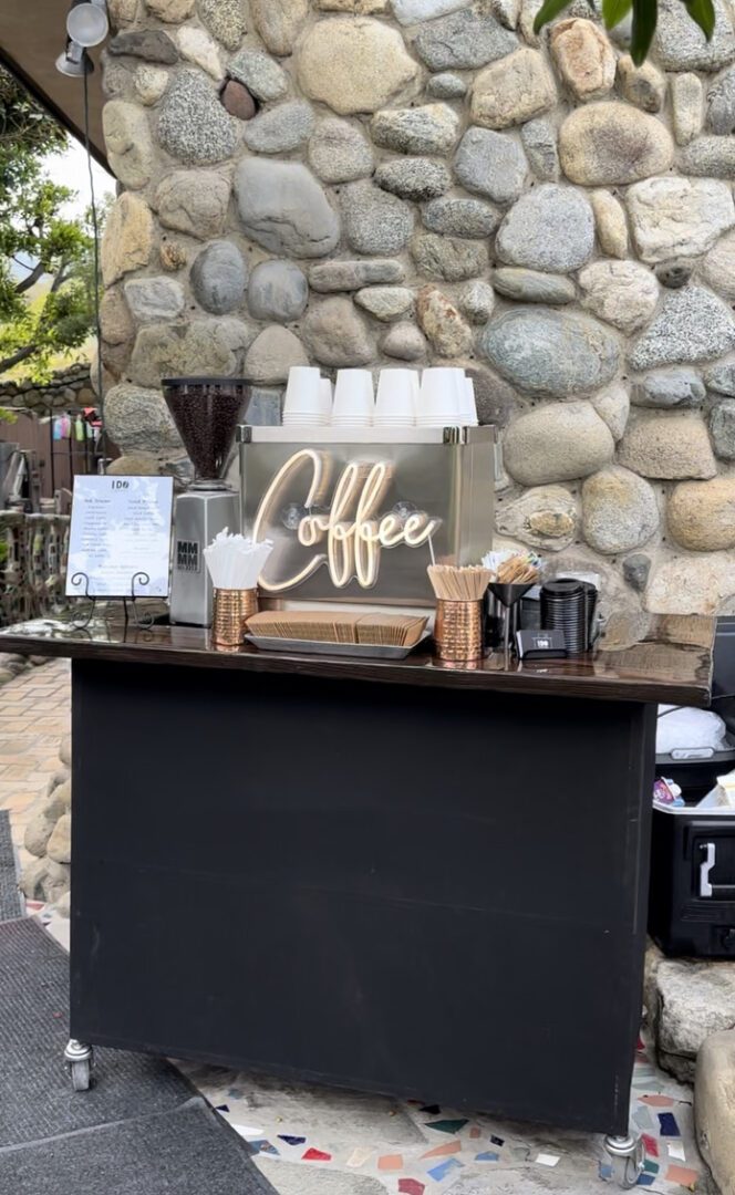 A coffee stand with cups of coffee on top.