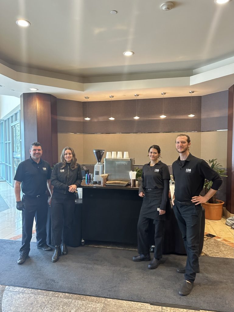 Four people standing in front of a coffee station.