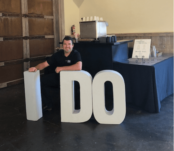 A man sitting in front of the word " i do ".